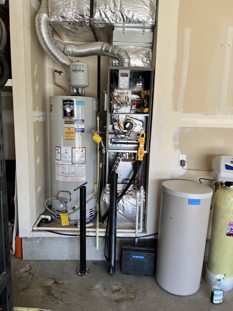 Residential HVAC mechanical room with gas water heater, electrical panel, ductwork, and supplementary water storage tanks installed.