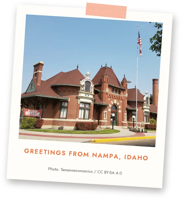 Historic red brick museum building with turrets and American flag in Nampa, Idaho postcard-style photograph.